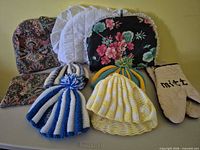All items grouped: knit and fabric tea cozies, oven mitt