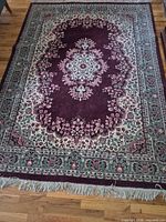 Full view of burgundy and ivory oriental rug on hardwood floor