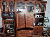 Front view of the entire medium-brown wood entertainment center showing glass display doors, central cabinet, drawers and side units