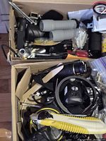 Overview of two boxes containing loose hand tools, flashlights, utility knife and cords