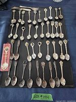 Full lot of souvenir spoons laid out on black mat