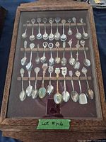 Entire glass-front wood case containing five rows of 30 souvenir spoons