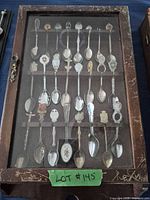 Full view of wooden display case containing 22 souvenir spoons