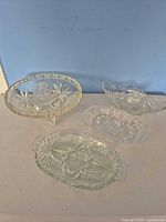 All four clear pressed glass serving pieces displayed together