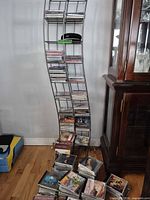 Full view of curved metal CD rack filled with CDs, additional stacks on floor