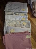 Stack of folded tablecloths with size notes including pink 60x80 and white 50x44