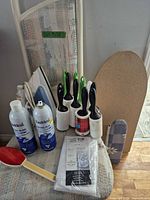 Group showing iron, ironing boards, lint rollers, starch cans, lint brush, laundry bag