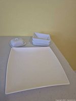 Square white porcelain plate with two small dishes and covered dish