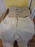 Four pairs of beige and cream bottoms stacked