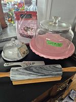Group shot showing large pink cake stand with dome, small dome stand, rolling pin, cake server, ornament, cupcake box pack
