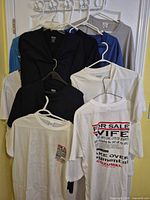 Eight assorted T-shirts hanging on hangers in various colours