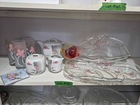 Full lot on shelf displaying glass platter, porcelain pieces, tumblers, candle, coaster