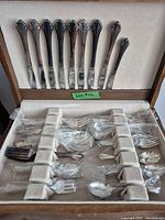 Open case showing knives in lid and wrapped flatware pieces