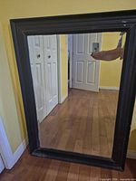 Front view of black framed rectangular wall mirror on floor