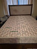 Full view queen mattress on bed frame with upholstered headboard