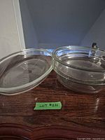 Three clear glass dishes stacked and one on side, showing overall condition