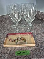 Eight clear stemmed wine glasses with boxed charms in foreground