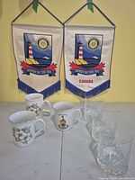 Group shot of two pennants, three mugs and three crystal tumblers