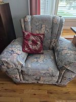 Full view of floral upholstered armchair with cushion