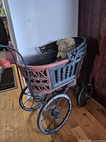 Side view of wicker doll stroller with bear inside
