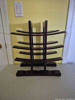 Front view of dark brown wooden wine rack showing four curved tiers and base