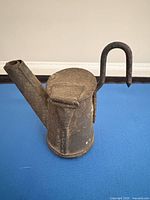 Side view showing spout, body, and hook of tin miner's lamp