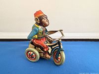 Left side view of tin monkey on tricycle