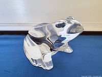 Left-front view of clear crystal Baccarat frog figurine on blue surface