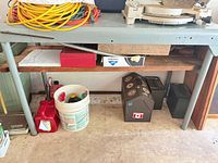 Front view of gray steel workbench showing wood top and wood lower shelf, contents on and below table not included