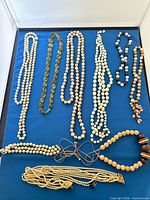 All nine necklaces laid out on blue surface