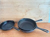 Three skillets stacked to show size range and handles