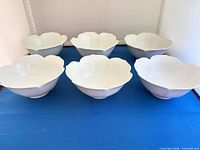 six white porcelain petal-rim bowls on display