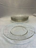 Stack of six clear Cornflower plates with floral cut pattern visible
