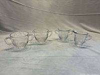 Four clear glass pieces: two creamers, two sugar bowls