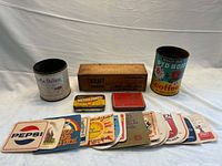 All items in lot: two large tins, wooden cheese box, two small tins, 15 beer mats