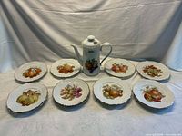 Full set showing coffee pot centered with eight of the fruit plates arranged around it