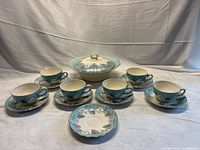 Full set laid out: covered serving dish, six teacups, seven saucers