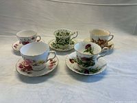 Five teacup and saucer sets displayed