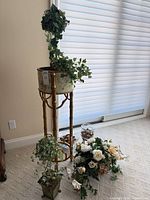 Tall gilt plant stand with planter and ivy topiary, small planter and flower arrangement alongside