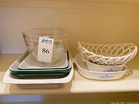 All items stacked on shelf: KitchenAid bowl, Emile Henry dishes, CorningWare dishes, ceramic basket