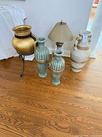 Group shot showing gold planter on stand, two green vases, lamp, cream urn