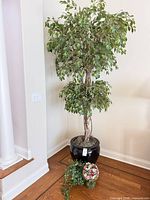 Full view of artificial ficus tree and small floral arrangement on floor