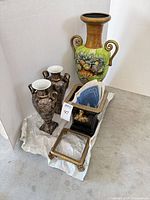Group shot of all items: large green urn, pair of floral vases, black cachepot with plates, picture frame