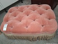 Overall view of ottoman showing tufted top and tag