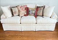 Full view of ivory three-seat sofa with six pillows