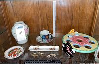 Full shelf view with vase, cup-saucer, plates, spoons, egg holder
