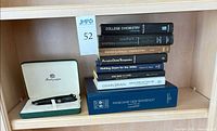 Pen in presentation box and stack of hardcover books on shelf