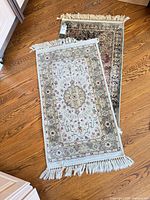 Two accent rugs stacked showing front patterns and fringe