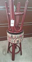 Pair of inverted wooden bar stools stacked showing reddish wood frames and round plaid seats