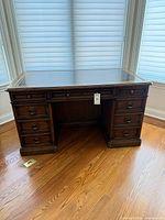 Front view of Sligh desk showing seven drawers and leather top